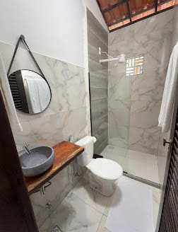 Banheiro da suíte com espelho redondo e box de vidro